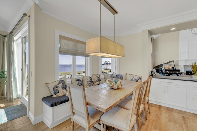 dining area featuring baseboards, light wood-style flooring, and crown molding