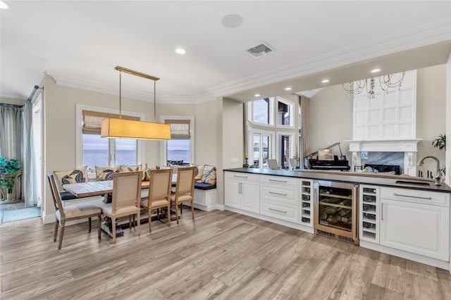 kitchen featuring a wealth of natural light, dark countertops, visible vents, a sink, and beverage cooler