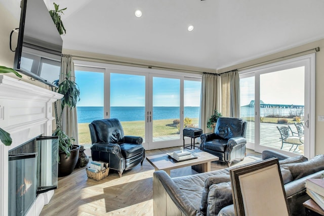 living area featuring recessed lighting, french doors, a water view, and a lit fireplace