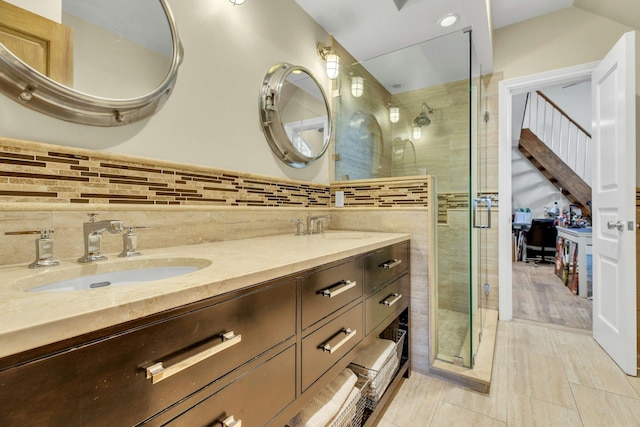 full bathroom featuring a stall shower, a sink, and double vanity