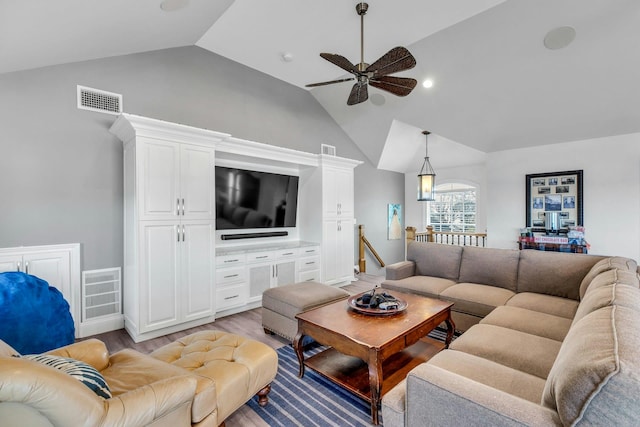 living area with light wood-type flooring, visible vents, vaulted ceiling, and ceiling fan