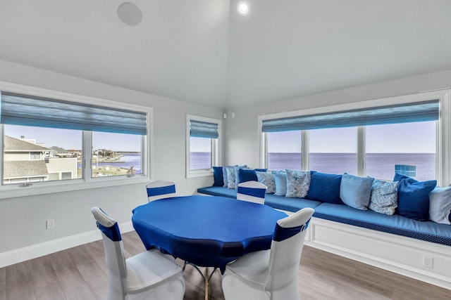 dining area featuring lofted ceiling, a water view, baseboards, and wood finished floors