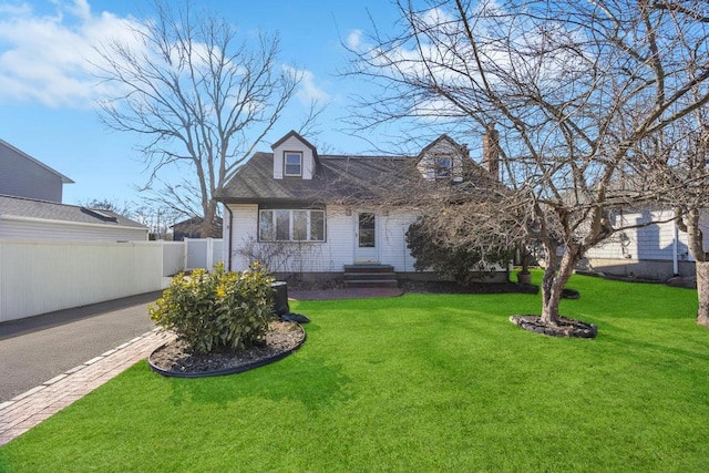 cape cod-style house with driveway, entry steps, fence, and a front yard