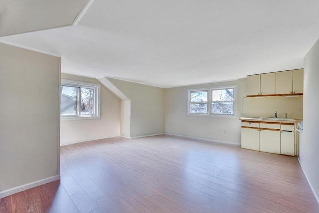 interior space with light wood-style floors, plenty of natural light, baseboards, and a sink