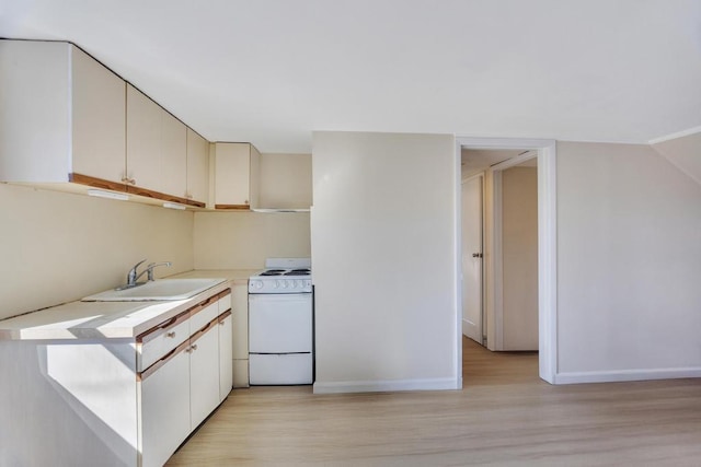 kitchen with white range with gas cooktop, baseboards, light countertops, light wood-style floors, and a sink