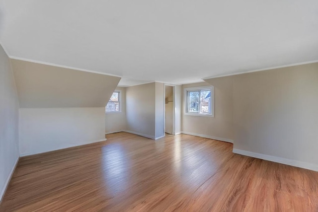 additional living space with lofted ceiling, light wood-style floors, and baseboards