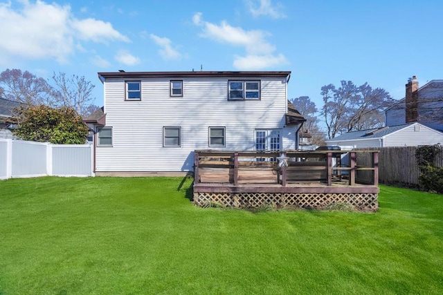 rear view of house with a fenced backyard, a deck, and a lawn