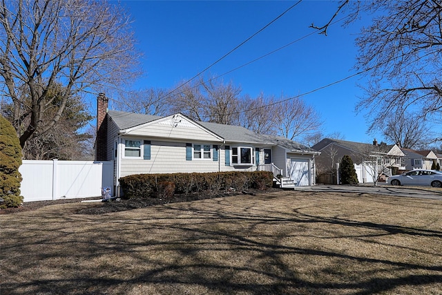 view of front of home with a chimney, an attached garage, and fence