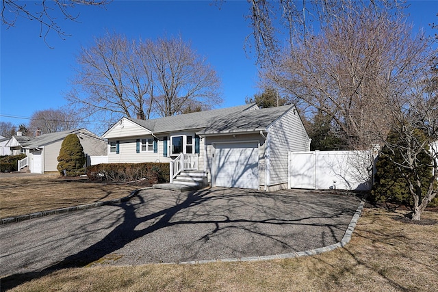 view of front facade featuring driveway, an attached garage, a chimney, and fence