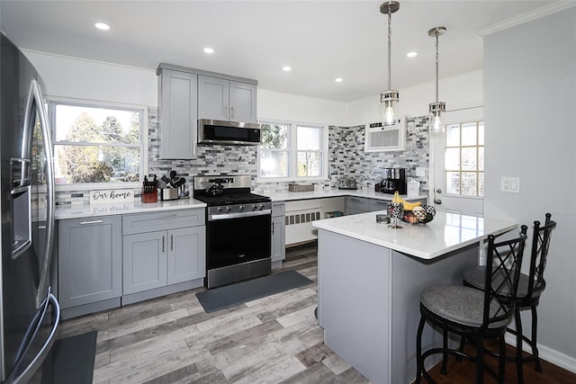 kitchen with tasteful backsplash, appliances with stainless steel finishes, a kitchen breakfast bar, and gray cabinetry