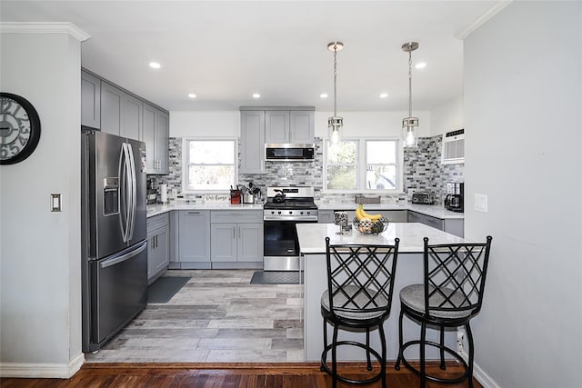 kitchen featuring appliances with stainless steel finishes, a wealth of natural light, light countertops, and gray cabinetry