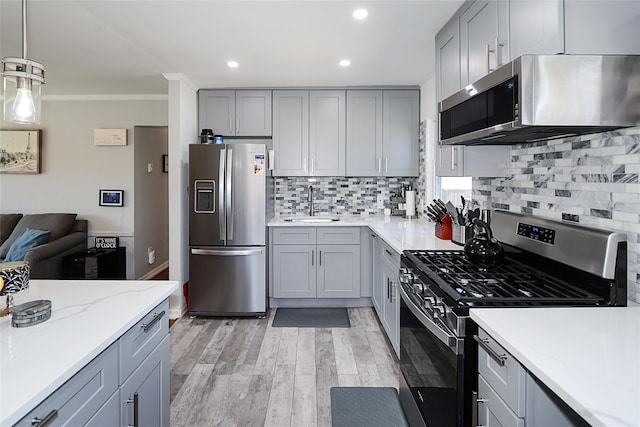 kitchen featuring appliances with stainless steel finishes, gray cabinets, a sink, and ornamental molding