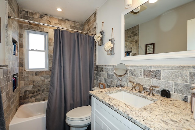 full bath with wainscoting, toilet, shower / bath combo with shower curtain, vanity, and tile walls