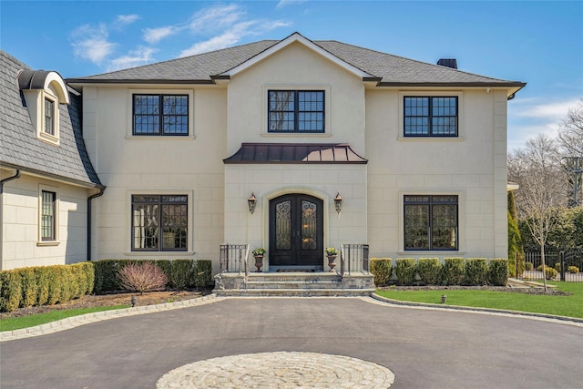 view of front of property with metal roof, fence, a standing seam roof, stucco siding, and french doors