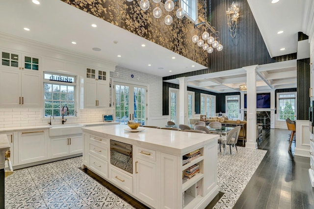kitchen featuring open floor plan, light countertops, a kitchen island, white cabinets, and wood finished floors