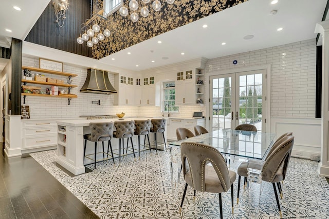 dining area featuring a wainscoted wall, french doors, a chandelier, a decorative wall, and recessed lighting