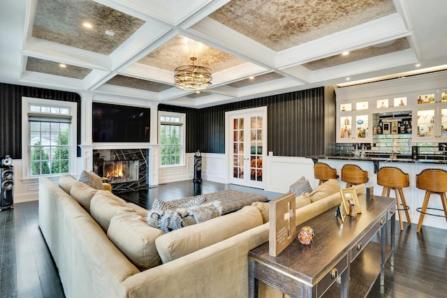living area with coffered ceiling, a notable chandelier, a premium fireplace, beamed ceiling, and dark wood-style flooring