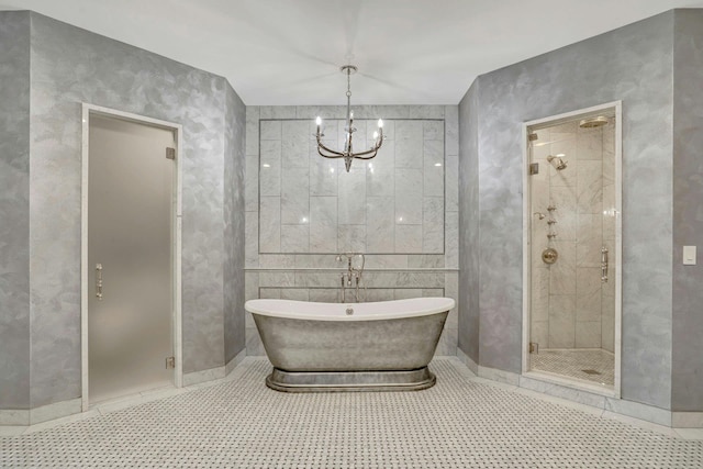 bathroom with a notable chandelier, a freestanding tub, and a shower stall