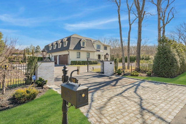 view of front of home with driveway, a gate, mansard roof, a shingled roof, and a fenced front yard