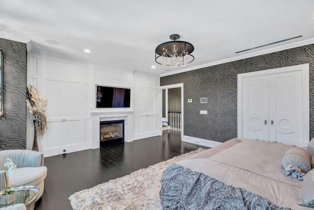 bedroom with ornamental molding, baseboards, wallpapered walls, a glass covered fireplace, and wood finished floors