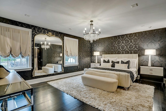 bedroom with dark wood-type flooring, baseboards, wallpapered walls, visible vents, and a notable chandelier