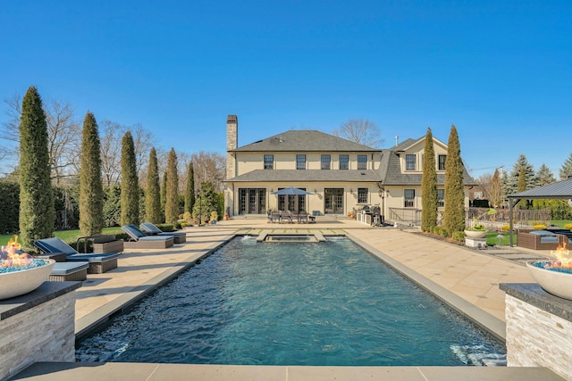 pool featuring a fire pit, an outdoor kitchen, a patio, and french doors
