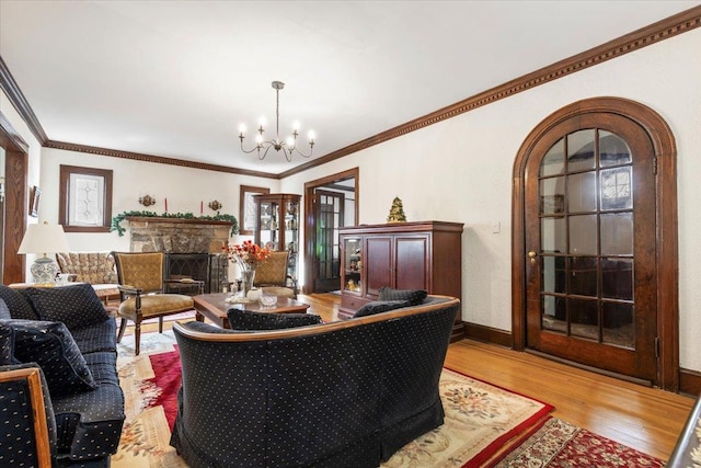 living room featuring baseboards, an inviting chandelier, a fireplace, arched walkways, and light wood-style floors