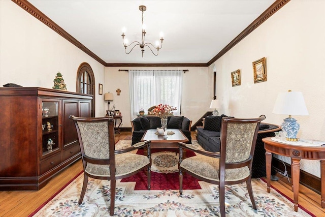 living area with an inviting chandelier, light wood-style floors, and ornamental molding