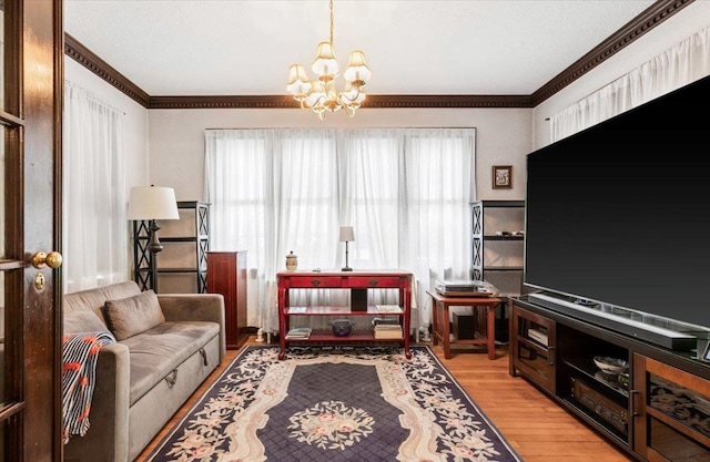 living room with an inviting chandelier, crown molding, and wood finished floors