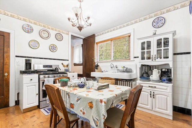 dining room with tile walls, a notable chandelier, and light wood finished floors