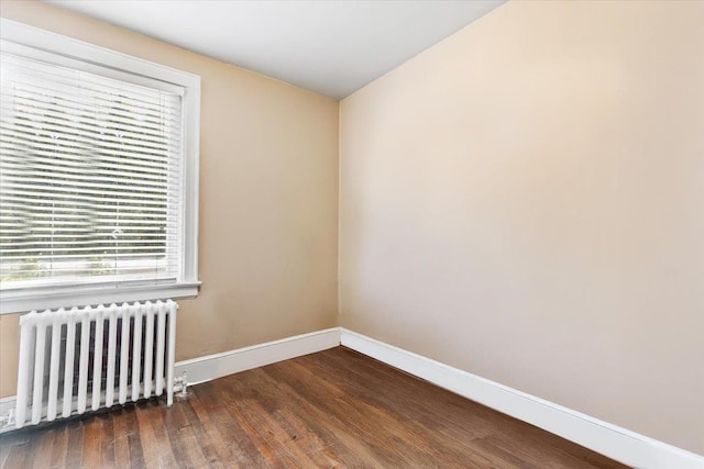 empty room featuring radiator heating unit, wood finished floors, and baseboards