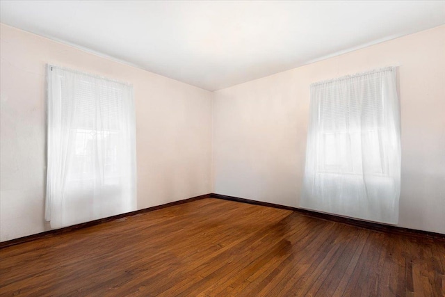 empty room with baseboards and wood-type flooring