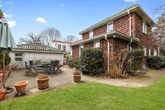 back of property with brick siding, a lawn, and a patio area