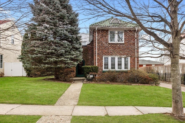 view of front of property featuring a front lawn, fence, and brick siding