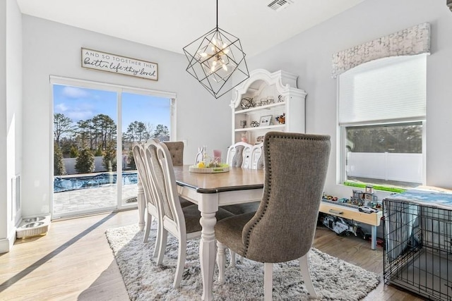 dining space featuring visible vents, a notable chandelier, and wood finished floors