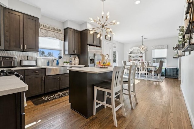 kitchen with light countertops, a sink, dark brown cabinetry, and stainless steel fridge with ice dispenser