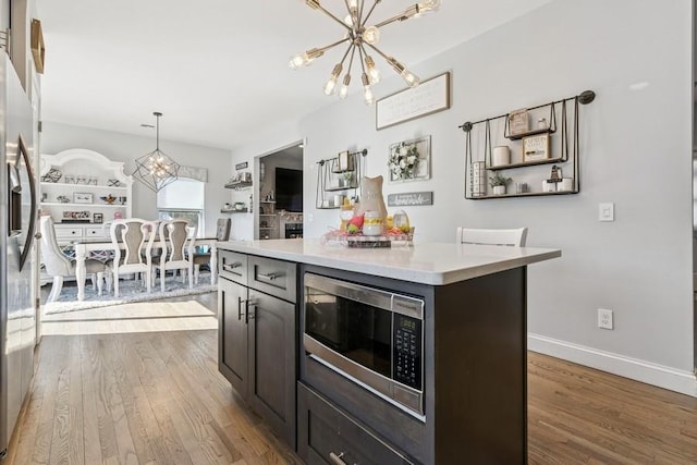 kitchen with a chandelier, stainless steel appliances, wood finished floors, and light countertops