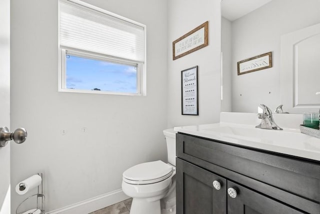 bathroom with baseboards, vanity, and toilet