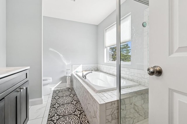 bathroom with toilet, a garden tub, vanity, and baseboards