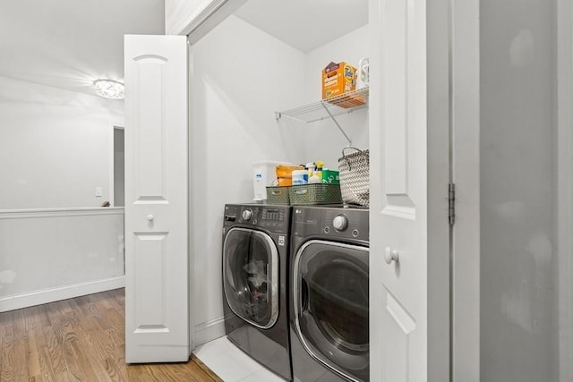 laundry room featuring laundry area, baseboards, washer and clothes dryer, and wood finished floors