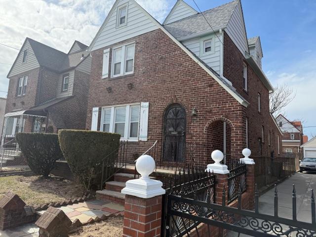 tudor house featuring fence and brick siding