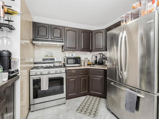 kitchen featuring dark brown cabinetry, under cabinet range hood, stainless steel appliances, a sink, and marble finish floor