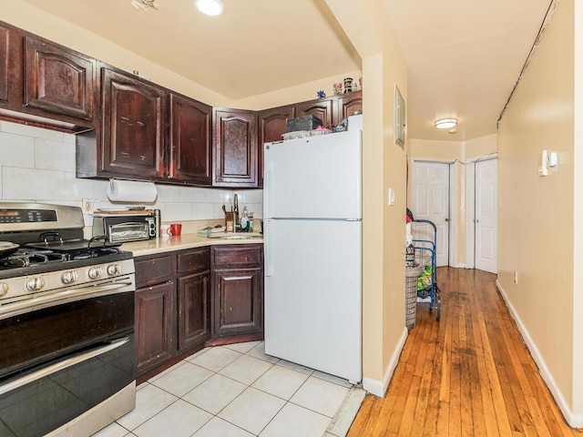 kitchen featuring range with two ovens, freestanding refrigerator, a sink, light countertops, and backsplash