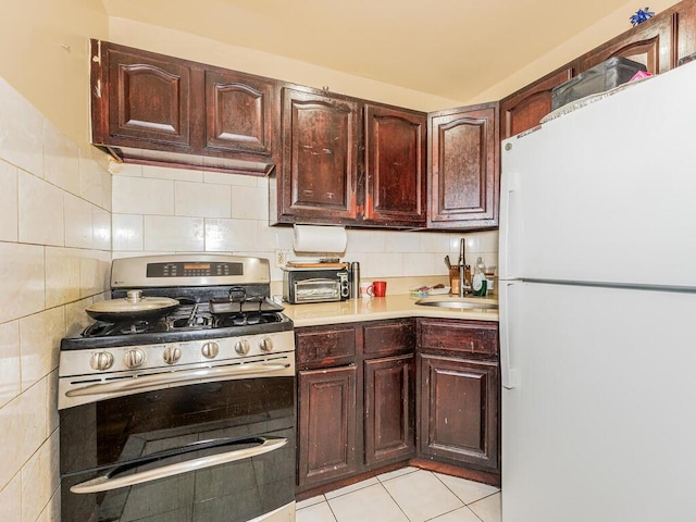 kitchen featuring freestanding refrigerator, light countertops, double oven range, backsplash, and light tile patterned flooring