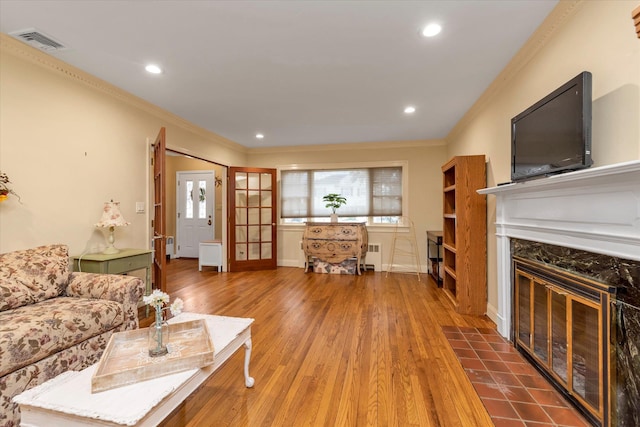 living room featuring radiator, visible vents, crown molding, and wood finished floors