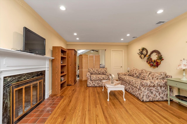 living room featuring ornamental molding, recessed lighting, a fireplace, and wood finished floors