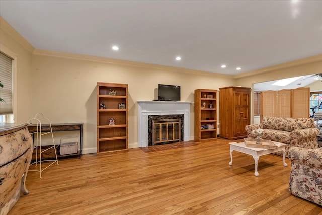 living area featuring ornamental molding, a skylight, light wood finished floors, and a premium fireplace