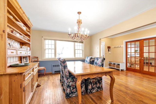 dining space with radiator, crown molding, light wood-style flooring, and french doors