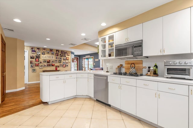 kitchen featuring visible vents, dishwasher, a peninsula, black microwave, and backsplash