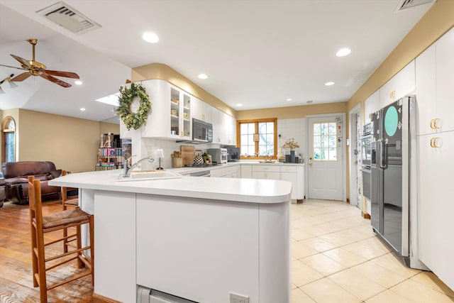 kitchen with a peninsula, a sink, visible vents, light countertops, and black appliances